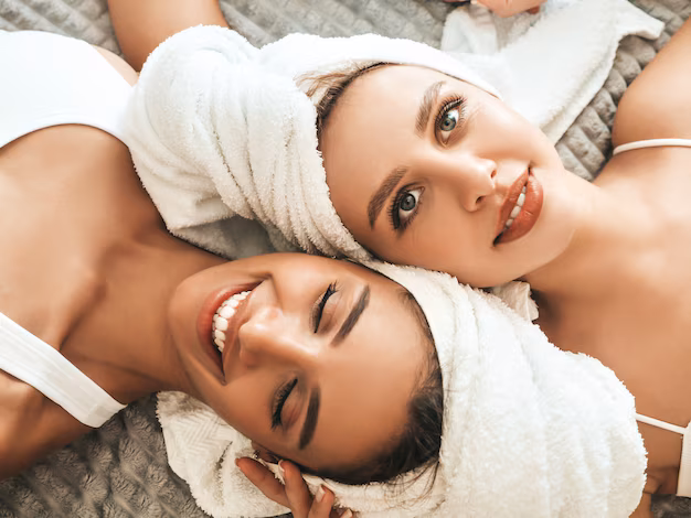 two-young-beautiful-smiling-women-white-bathrobes-towels-head_158538-18141